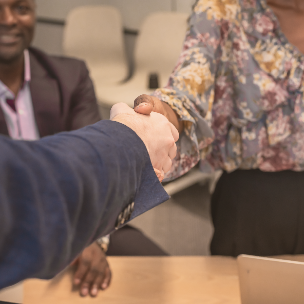 Apretón de manos entre dos personas de diferentes contextos en un entorno profesional.