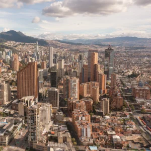 Vista aérea de Bogotá al atardecer con edificios y montañas.